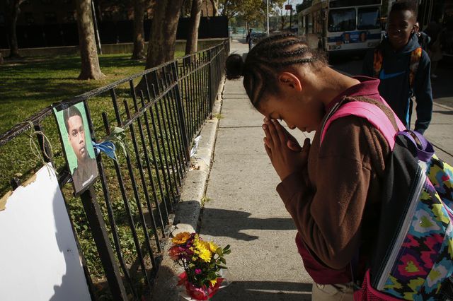 A girl prays at a makeshift memorial for police officer Randolph Holder outside the Wagner Houses community center.